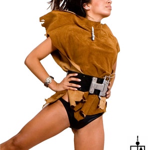 May include: A woman wearing a brown suede top with a black belt and a silver buckle. She is also wearing a black bikini bottom. Her hair is long and brown and she is looking up.
