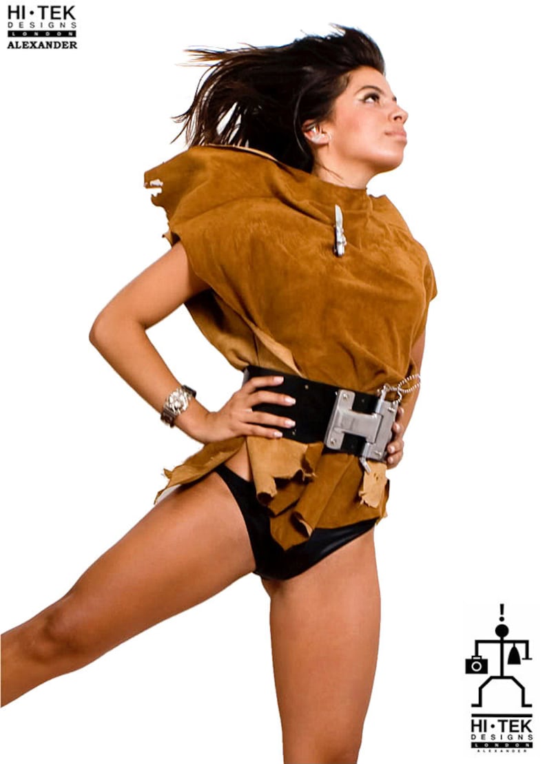 May include: A woman wearing a brown suede top with a black belt and a silver buckle. She is also wearing a black bikini bottom. Her hair is long and brown and she is looking up.