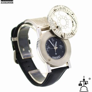 May include: A silver wristwatch with a black face and a rotating bezel. The watch has a black leather band and is water resistant to 30 meters. The watch face features a unique design with stick hands and a small window displaying the date.