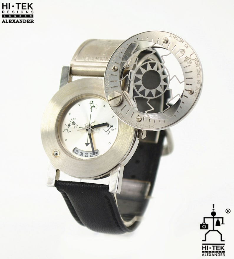 May include: A silver wristwatch with a white face and black leather band. The watch has a unique design with a rotating compass dial and a small window displaying the date. The watch face features a stylized running figure and the text "HI-TEK DESIGNS LONDON ALEXANDER".