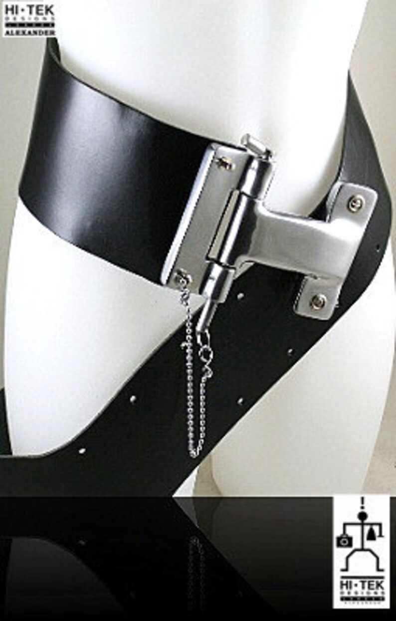 May include: A black leather belt with a silver metal buckle and a chain attached. The buckle is shaped like a hinge and has a small metal loop on the side. The belt is worn on a mannequin.