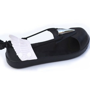 May include: Black sandals with a white wing detail on the side. The sandals have a silver spike on the toe and a black strap across the foot.