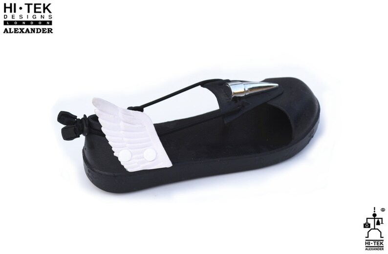 May include: Black sandals with a white wing detail on the side. The sandals have a silver spike on the toe and a black strap across the foot.