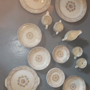 May include: A collection of vintage china with a floral center design and gold trim. The set includes plates of various sizes, bowls, cups, a creamer, a sugar bowl, and a gravy boat. The china is white with a delicate pattern.