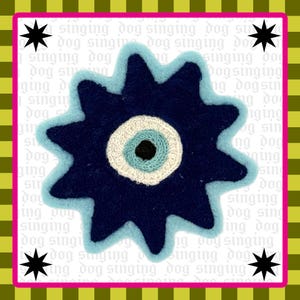 May include: A star-shaped patch featuring a dark blue center, a light blue ring, and a white outer circle, resembling an eye. The background is white with repeating text reading singing dog, framed by a lime green and black checkered border.