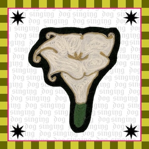 May include: A decorative patch featuring a calla lily design. The lily is cream-coloured with gold accents, outlined in black, and has a green stem. The background includes the text "singing dog" and star shapes.