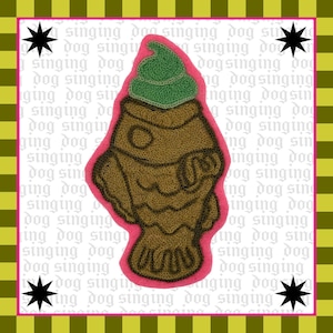 May include: A brown, textured patch in the shape of a fish with a green topping, outlined in pink. The background is a repeating pattern of text and a striped border with star accents. The text reads "singing dog".