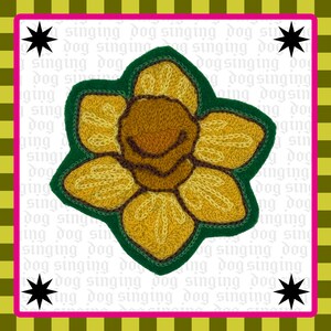 May include: An embroidered patch featuring a yellow and orange daffodil flower with a dark green border. The background is white with the repeating text "singing dog" in light gray, framed by a lime green and black border with four black stars.