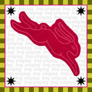 Peut inclure: Une œuvre fantaisiste avec une silhouette de lapin rouge cousue, sur un fond de texte répété « singing dog ». L'œuvre est encadrée d'une bordure rose, d'étoiles noires et d'un motif rayé vert et jaune.