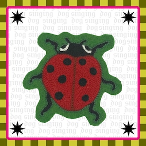 May include: A red ladybug patch with black spots and a black head, embroidered on a green felt backing. The background is white with the repeating text "singing dog" and four black star icons in the corners, framed by a pink and olive border.