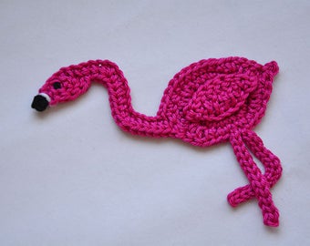 Puede incluir: Un flamenco de crochet rosa con un ojo negro y un pico blanco.