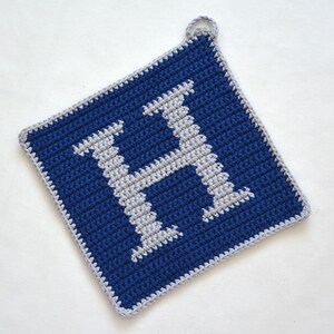 Peut inclure: Un porte-pot en crochet bleu et gris avec la lettre H au centre.