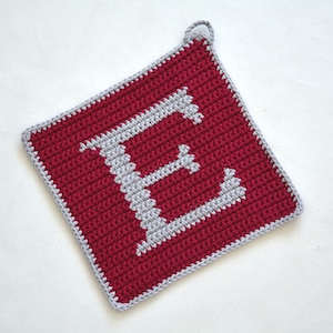 May include: A red crocheted pot holder with a white letter E in the center.