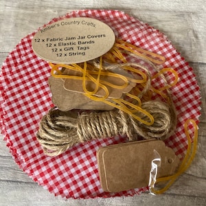 May include: A set of 12 red and white gingham fabric jam jar covers, 12 elastic bands, 12 brown gift tags, and 12 pieces of twine. Amber's Country Crafts.