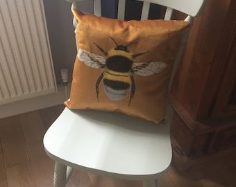 May include: A white wooden chair with a yellow velvet cushion featuring a large bumble bee illustration.