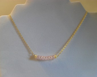 Girly and sophisticated pink faceted rondelle and gold-plated filigree bar necklace