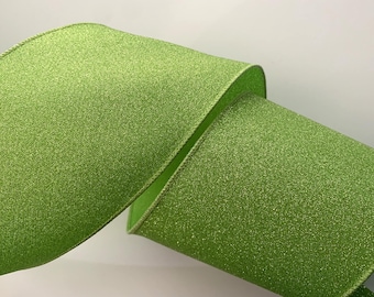 May include: Close-up of a roll of bright green ribbon with a glittery texture. The ribbon is curled, revealing its edges and inner side. The edges are trimmed with a thin, darker green border.