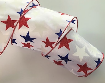 May include: White ribbon with red and blue stars printed on it. The ribbon has a red wired edge.