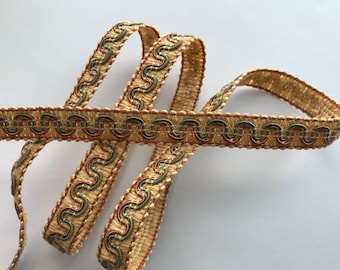 May include: A close-up of a gold, green, and orange trim with a wavy pattern. The trim is made of woven fabric and is approximately 1 inch wide.
