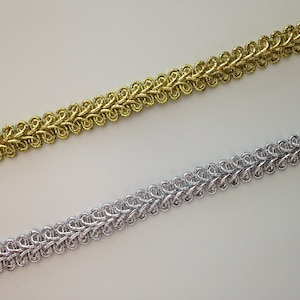 May include: Two pieces of decorative trim, one gold and one silver, with a looped design.
