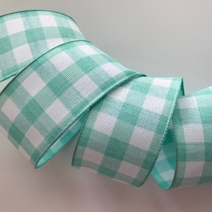 May include: A roll of mint green and white gingham ribbon. The ribbon is woven with a checkered pattern.