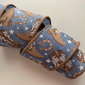 May include: Blue and brown ribbon with a western theme. The ribbon features cowboy boots, stars, and horseshoes.