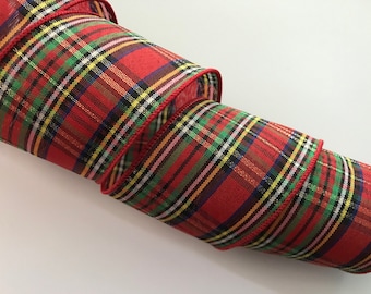 May include: Red and green plaid ribbon with a wired edge. The ribbon is rolled up and has a shiny finish.