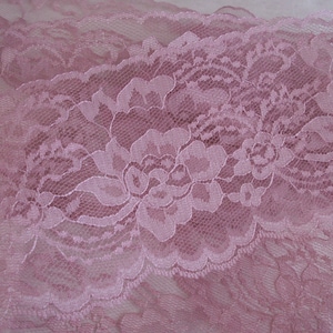 May include: Pink lace trim with a floral pattern. The lace is delicate and has a soft, feminine look.