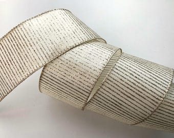 May include: White ribbon with gold glitter stripes. The ribbon is rolled up and has a soft, shimmery texture.