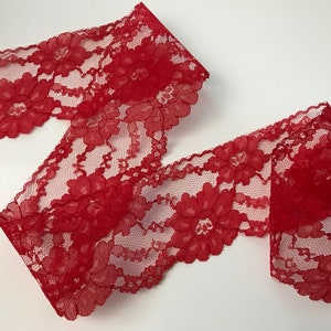 May include: Red lace trim with a floral pattern. The lace is delicate and has a scalloped edge.