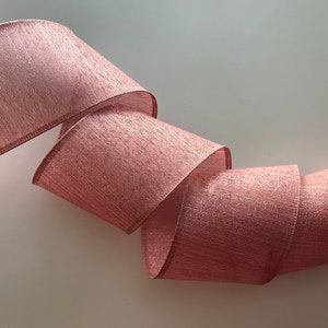 May include: A roll of pink and silver shimmer ribbon. The ribbon has a textured, woven look.