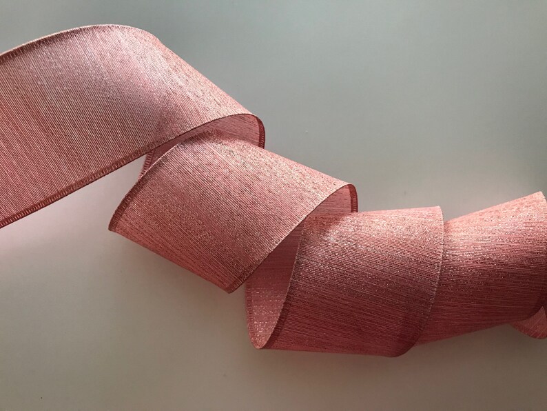 May include: A roll of pink and silver shimmer ribbon. The ribbon has a textured, woven look.