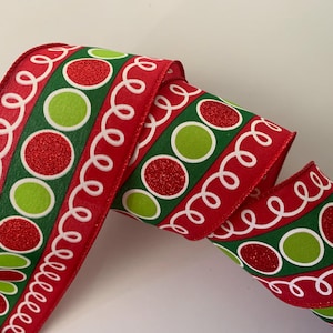May include: Red ribbon with a festive design featuring green and red circles, and white swirly accents. The ribbon is likely used for gift wrapping or holiday decorations.