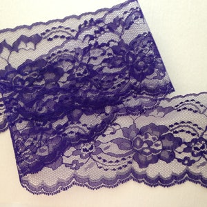 May include: Purple lace trim with a floral pattern. The lace has a scalloped edge.