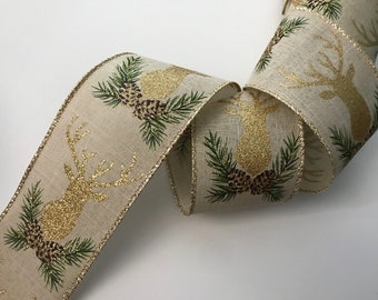 May include: A roll of decorative ribbon with a natural linen texture. The ribbon features a repeating pattern of gold glitter deer heads, green pine needles, and brown pine cones. The edges are trimmed with gold metallic thread.