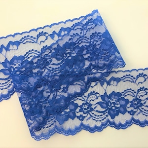 May include: A close-up of a blue lace trim with a floral pattern. The lace is delicate and has a scalloped edge.