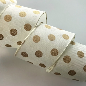 May include: A roll of ivory-colored ribbon with a repeating pattern of large, gold polka dots. The ribbon has a textured appearance and a stitched edge. This decorative ribbon is suitable for crafts, gift wrapping, and various DIY projects.