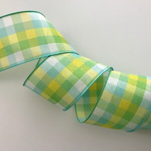 May include: Green, yellow, and blue plaid ribbon with a white background. The ribbon has a green edge.