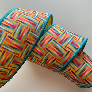 May include: A colorful ribbon with a woven pattern in shades of yellow, orange, red, green, and blue. The ribbon has a teal edge.