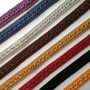 May include: Assortment of braided trim in various colors, including purple, blue, silver, brown, gold, red, black, and yellow. The trim is made of a woven material and has a decorative, looped design.
