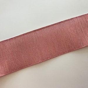 May include: A close-up of a pink satin ribbon with a subtle shimmer. The ribbon has a textured surface and is perfect for adding a touch of elegance to any project.