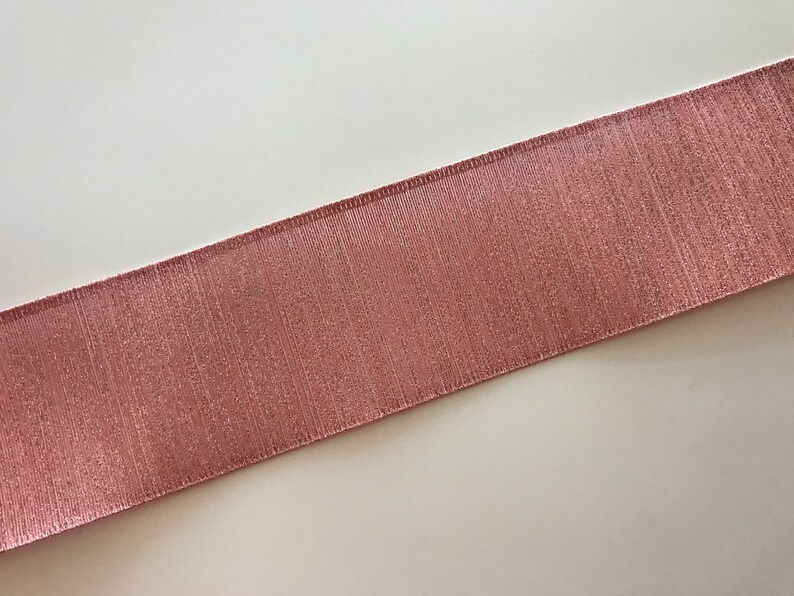 May include: A close-up of a pink satin ribbon with a subtle shimmer. The ribbon has a textured surface and is perfect for adding a touch of elegance to any project.