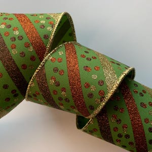 May include: Green ribbon with gold trim, featuring diagonal stripes of glittery gold and brown, and scattered gold and brown polka dots. The ribbon is curled, showing its texture and design.