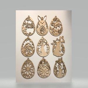 May include: Nine wooden Easter egg ornaments with intricate cut-out designs. Some eggs feature bunnies, flowers, and the words "Happy Easter." The ornaments are light brown and have small holes for hanging. These decorations are perfect for Easter.