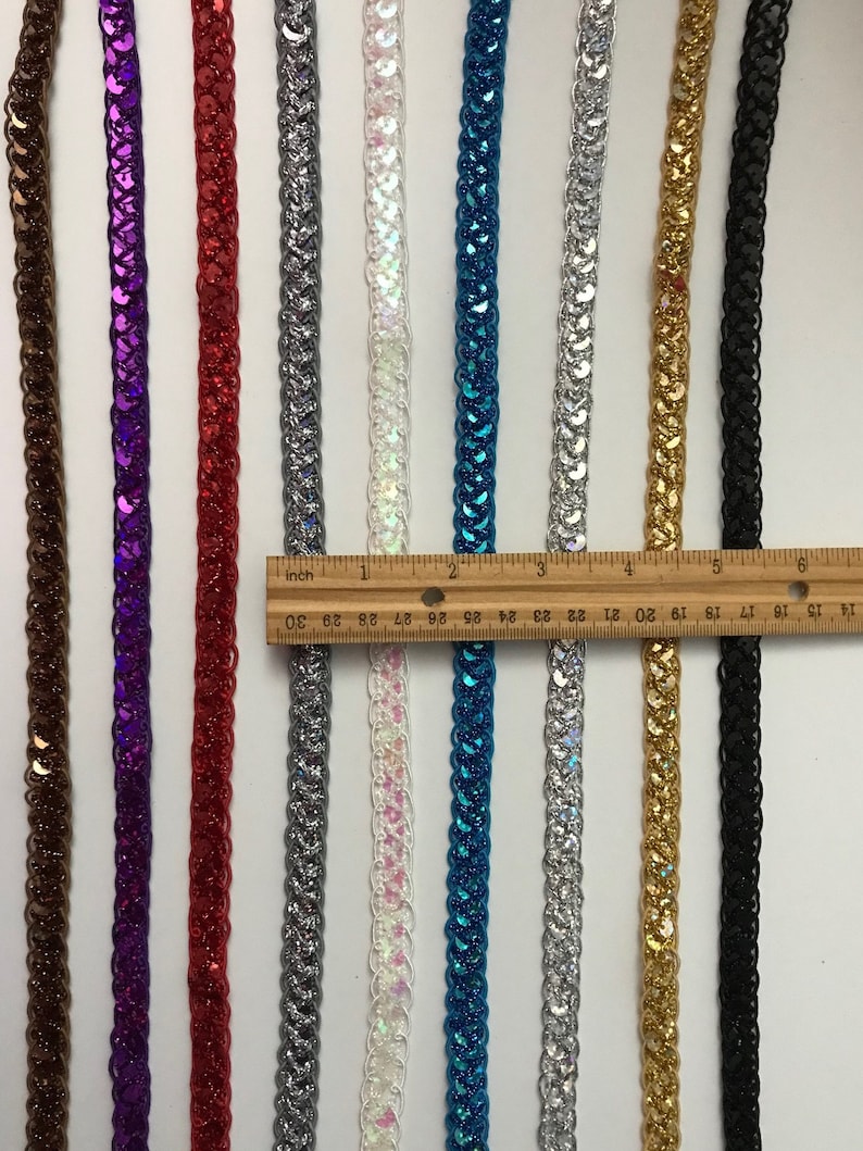 May include: Ten strands of sequined trim in various colors, including brown, purple, red, silver, white, blue, gold, and black. The trim is approximately 30 inches long.