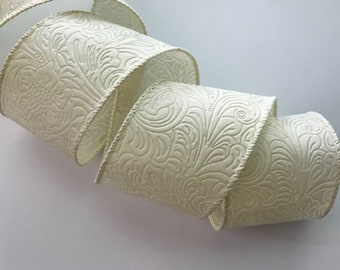 May include: Cream-colored satin ribbon with an embossed floral pattern. The ribbon is curled and has a wired edge.