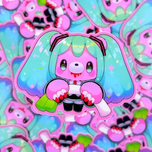 Puede incluir: Una pegatina rosa con un oso de dibujos animados con pelo turquesa y boca roja. El oso tiene ojos grandes y sostiene un objeto blanco. La pegatina tiene un borde rosa y está rodeada de otras pegatinas.