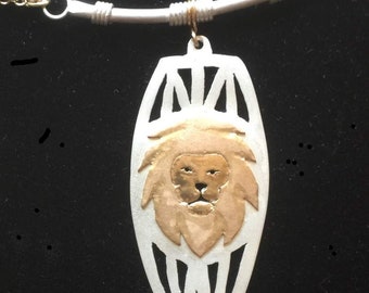 Kavango Gold lion necklace on silver drum background with suspension bar and chain