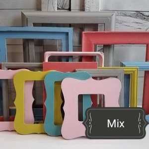 May include: A collection of colorful, empty picture frames in various shapes and sizes. The frames are painted in shades of pink, blue, yellow, and gray. A black sign with the word "Mix" is in the foreground.