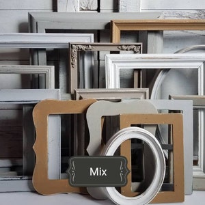May include: A collection of various picture frames in different shapes and sizes. The frames are painted in neutral colors like white, gray, and tan. Some frames have ornate details, while others are simple. The word "Mix" is displayed on a label.